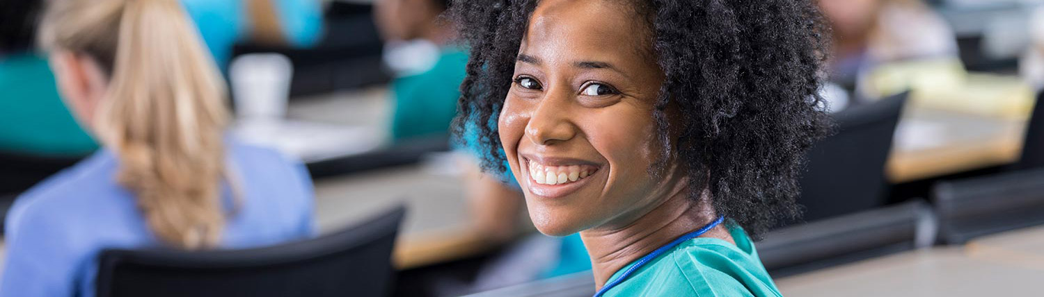 Smiling woman in a classroom wearing scrubs