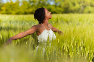 Woman standing in tall grass with her arms spread