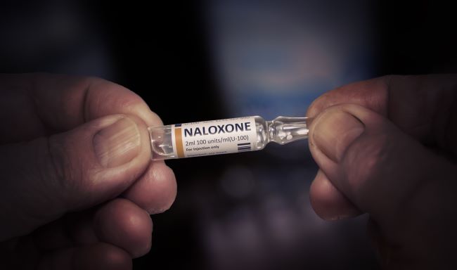 Hands holding a naloxone vial