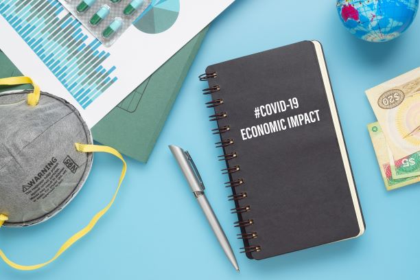 Journal that says COVID-19 economic impact, a pen, an n-95 mask, pills, a mini globe, and money