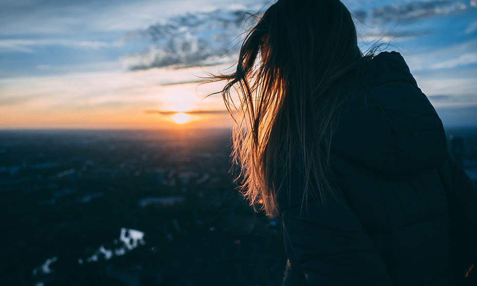 Person standing near an ocean during sunrise