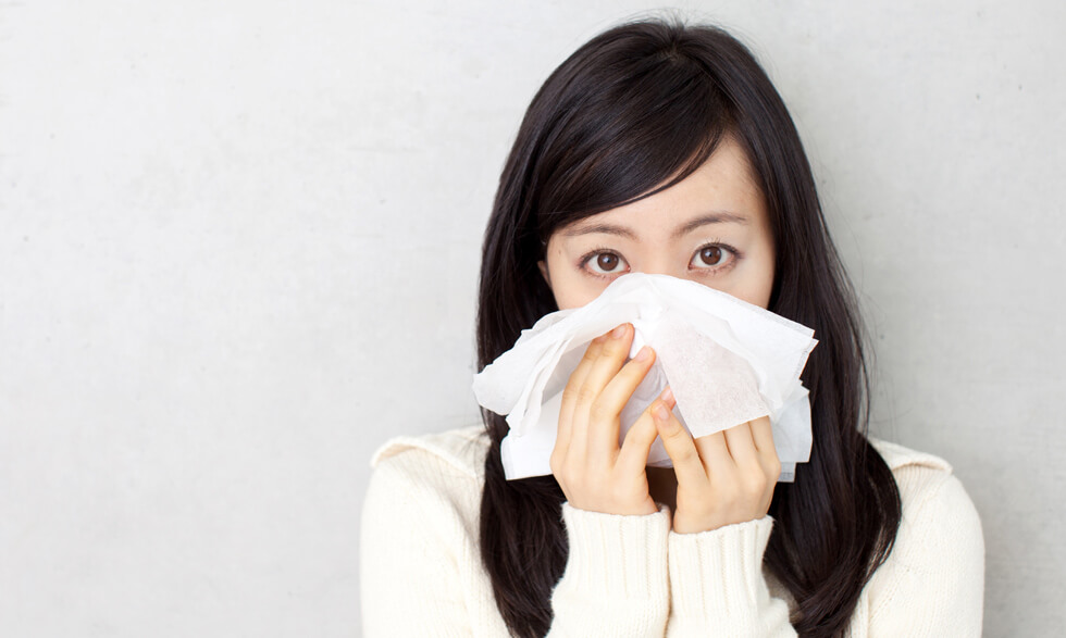 Woman covering nose and mouth with a tissue