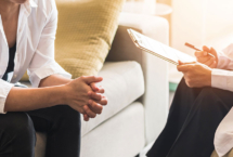 Patient on couch and doctor holding clipboard