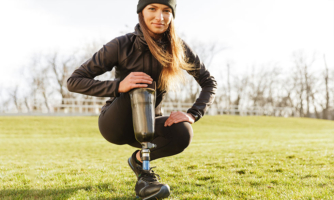 Woman in field gesturing to her prosthetic leg