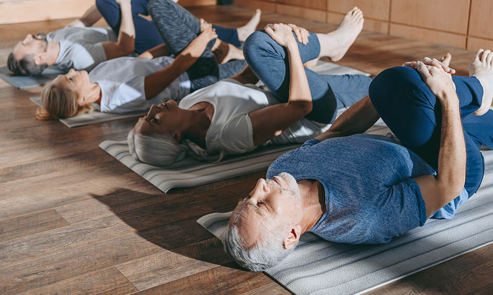 Four people of varying ages doing yoga on mats