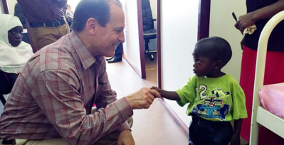 Russell E. Ware M.D., Ph.D., shaking hands with a young sickle cell patient in Africa.
