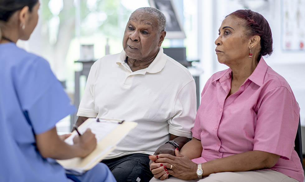 Two elderly individuals talking to a doctor or nurse practitioner