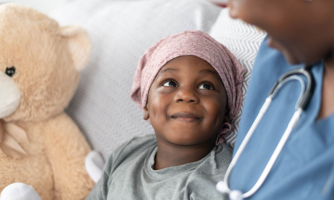 Young girl with cancer smiling at nurse
