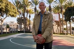 Kareem Abdul-Jabbar standing on an outdoor basketball court.